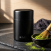 Kokuyō Chazutsu matcha canister on slate with a matcha bowl and whisk