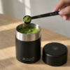 Hand scooping matcha from the Kokuyō Chazutsu tea canister with the Shukaku scoop